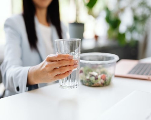 A person taking a mindful break during office hours to drink clean water in a bright room