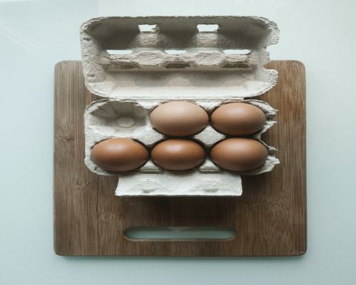 Fresh boiled eggs sliced on a wooden board indicating everyday simple protein source